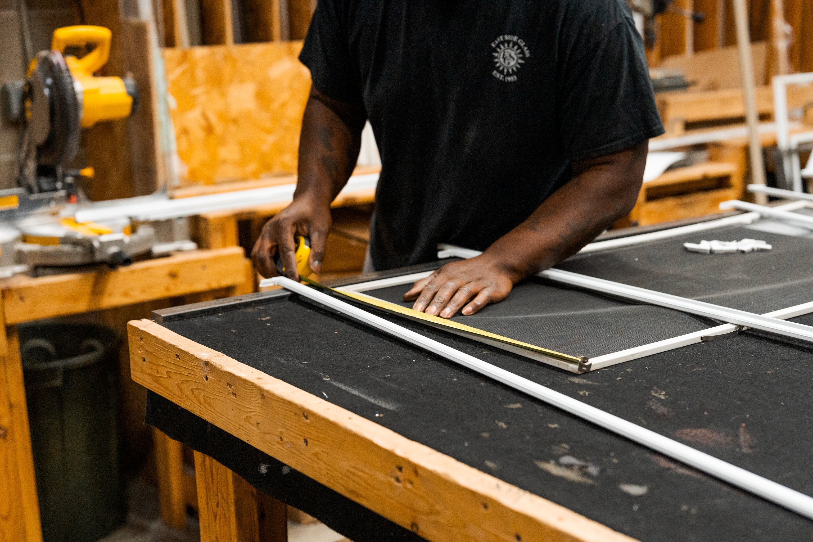 man measuring window screen in workshop
