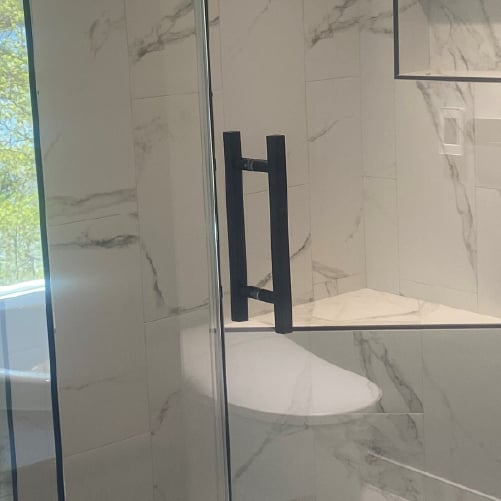 Glass shower door with black handle
